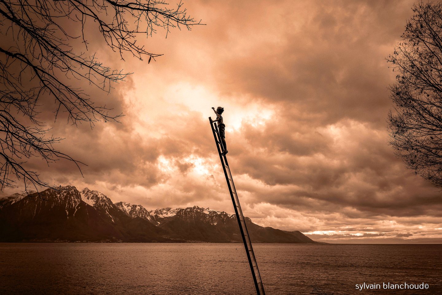 Un ciel d'orage cuivré au-dessus du lac et des montagnes ; une petite silhouette se tient au sommet d'une longue échelle penchée.